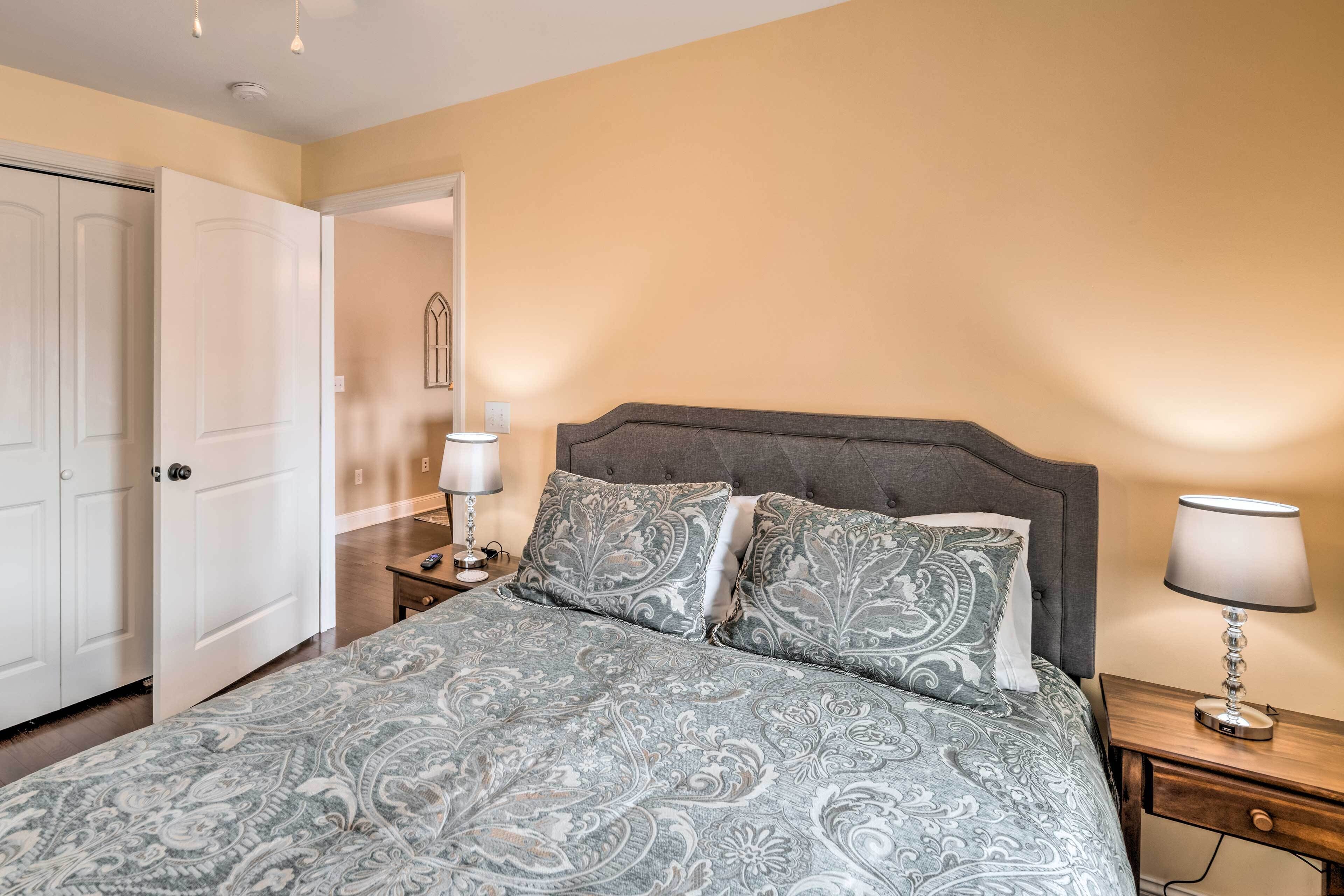 A bedroom with a bed, nightstands, a lamp, and a door.