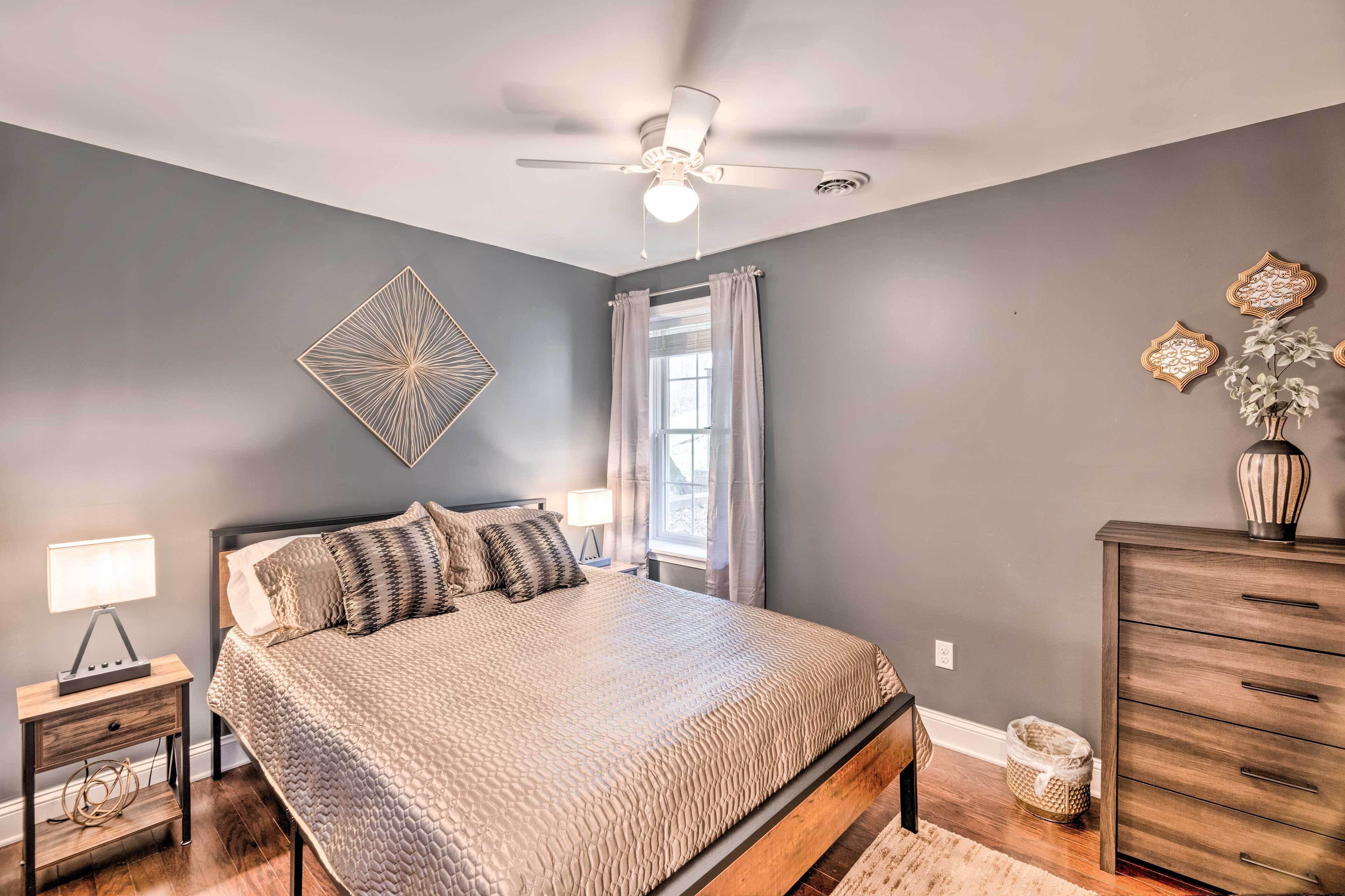 A bedroom with a bed, nightstand, dresser, and a ceiling fan.