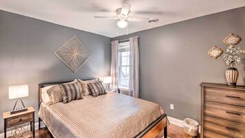 A bedroom with a bed, nightstand, dresser, and a ceiling fan.