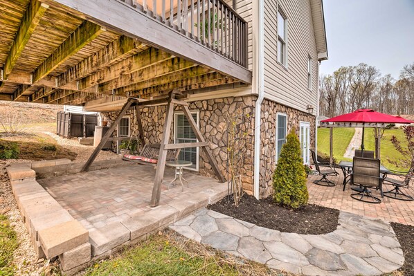 A covered outdoor patio with stone steps, a wooden swing set, and a red umbrella. - Bristol Escape w/ Patio, 2 Mi to Downtown! (Bristol)