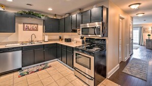 A modern kitchen with dark cabinets, stainless steel appliances, and a decorative backsplash. - Bristol Escape w/ Patio, 2 Mi to Downtown! (Bristol)