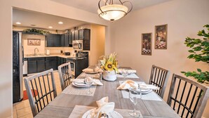 A dining area with a wooden table set for four, surrounded by chairs. A chandelier hangs above, and there are framed pictures on the wall. - Bristol Escape w/ Patio, 2 Mi to Downtown! (Bristol)