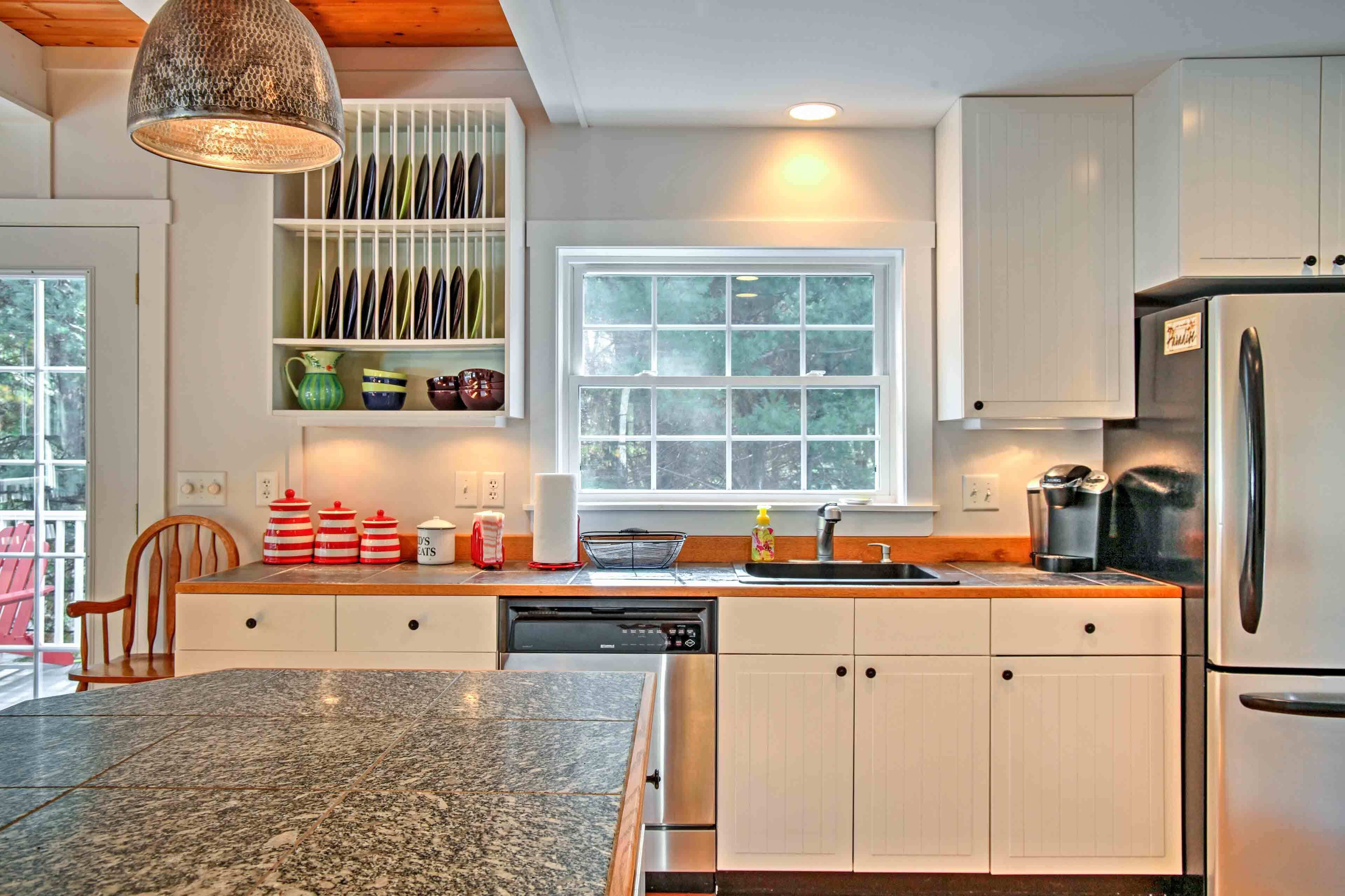 A modern kitchen with white cabinets, a granite countertop, a dishwasher, and a refrigerator.