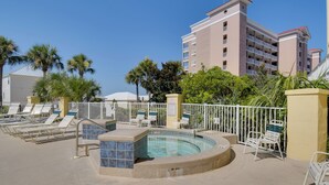 Ein Poolbereich mit Liegestühlen und einem Whirlpool, umgeben von einem weißen Zaun und Palmen.