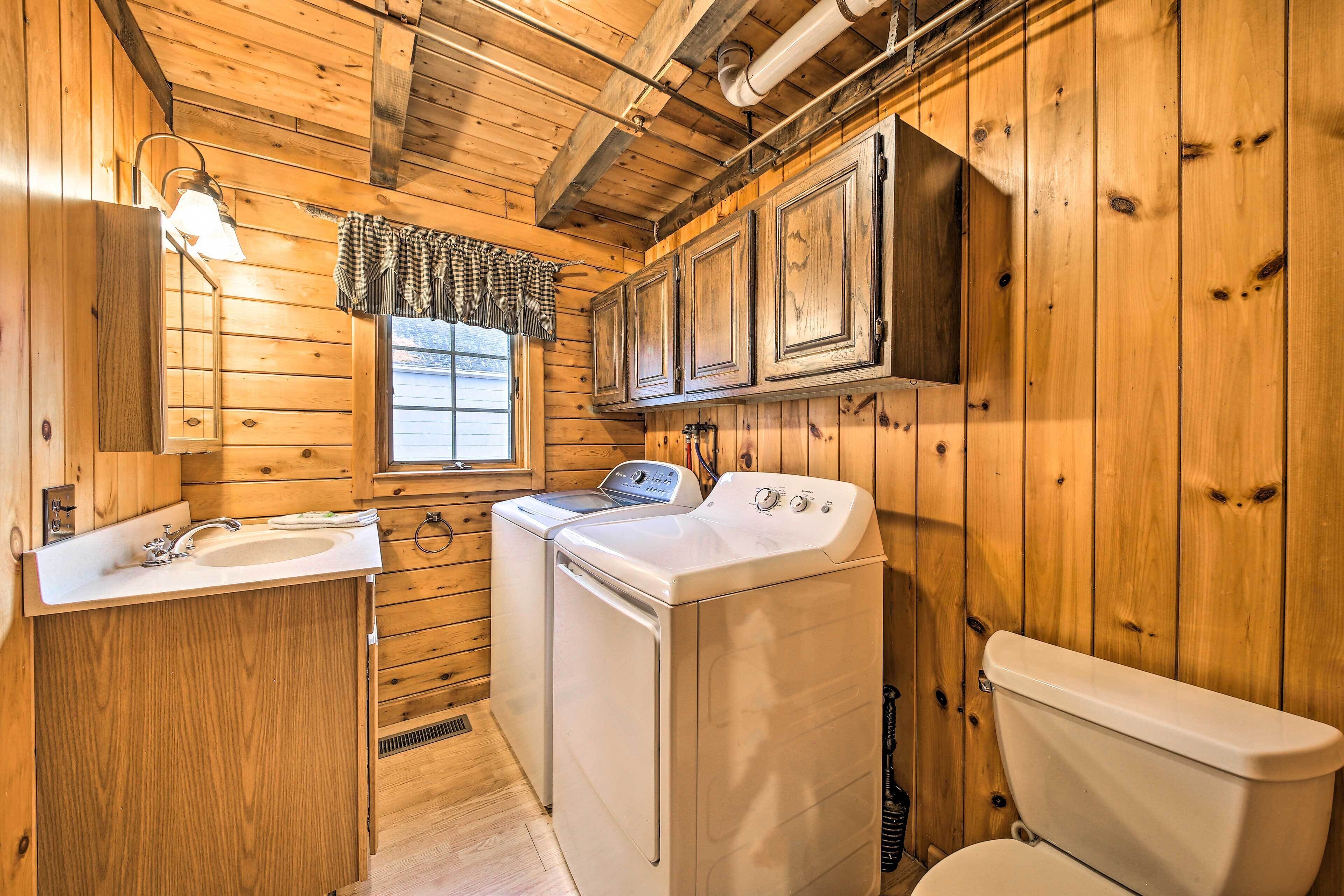 Baño de cabaña de madera con lavamanos, lavadora e inodoro.