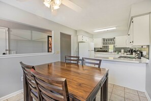 A modern kitchen with white cabinets, a wooden dining table, and a built-in oven. - Auburn Home w/ Private Yard < 4 Mi to Campus! (Auburn)