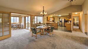 A spacious living area with a round dining table and chairs, a chandelier, and a view through large windows. - Buena Vista Retreat: 7 Acres & Panoramic Views (Buena Vista)