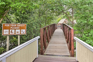 Un pont piétonnier en bois, doté de panneaux de signalisation et d’une rambarde métallique.