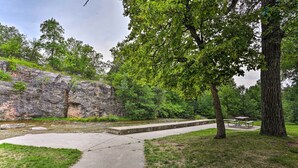 A park with a concrete path, picnic tables, and a large tree. - Central Creekfront Spearfish Apt by City Park (Spearfish)
