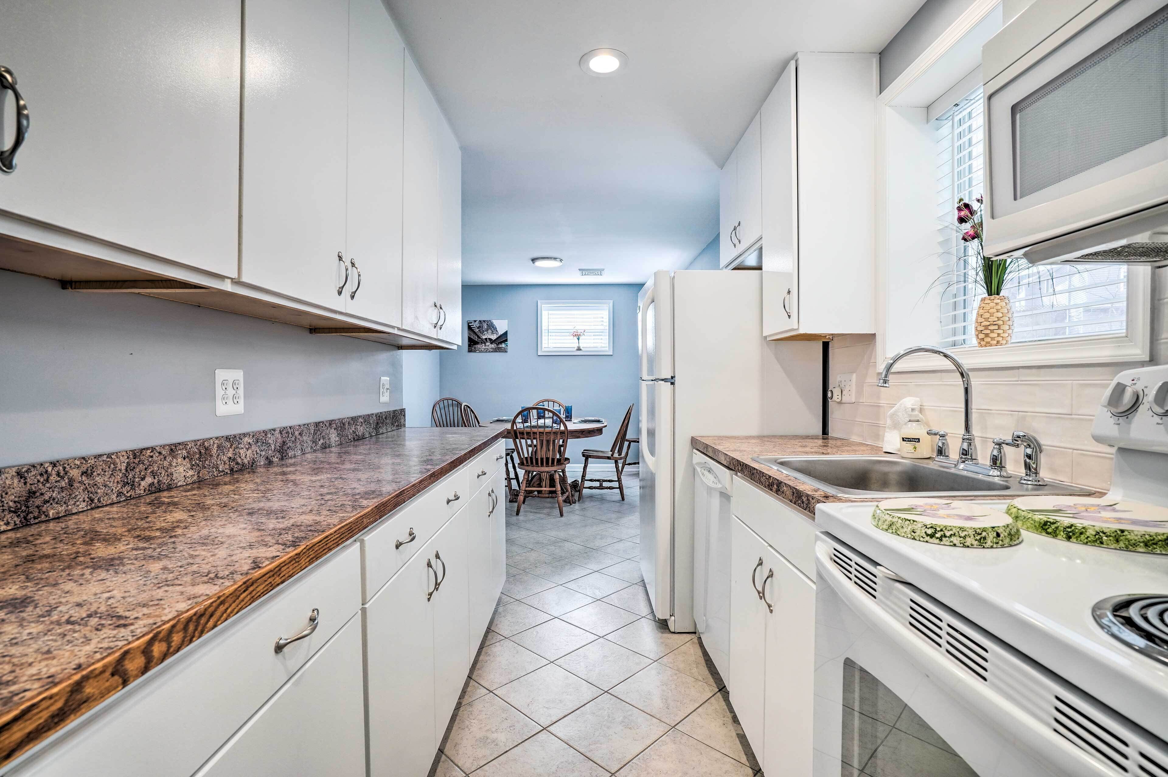 A modern kitchen with white cabinets, granite countertops, and a dining area in the background.