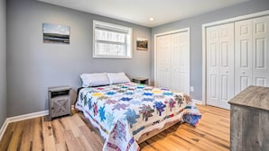 A bedroom with a bed, two nightstands, a window, and a door.