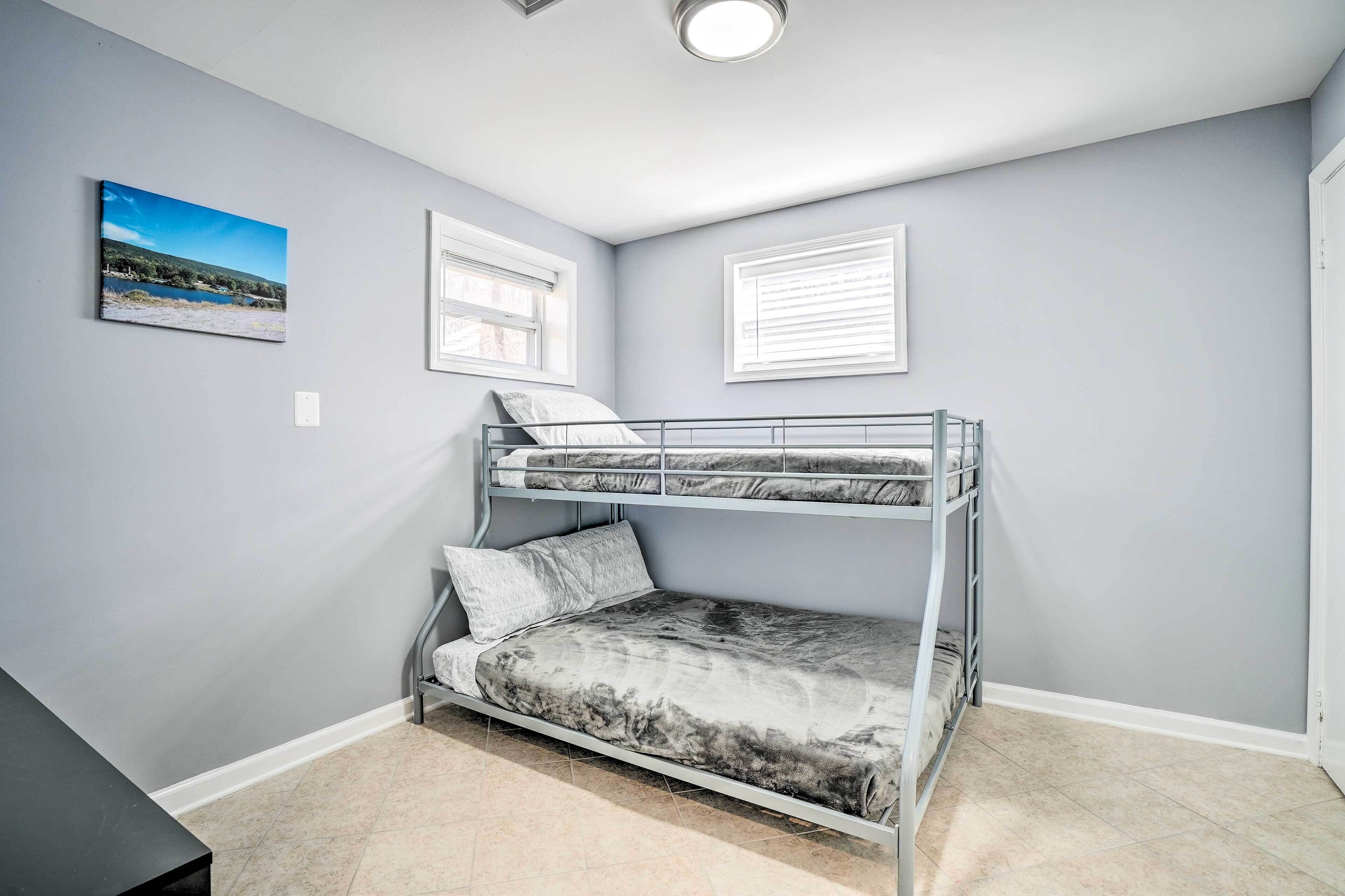 A bedroom with a bunk bed, a window with blinds, and a painting on the wall.