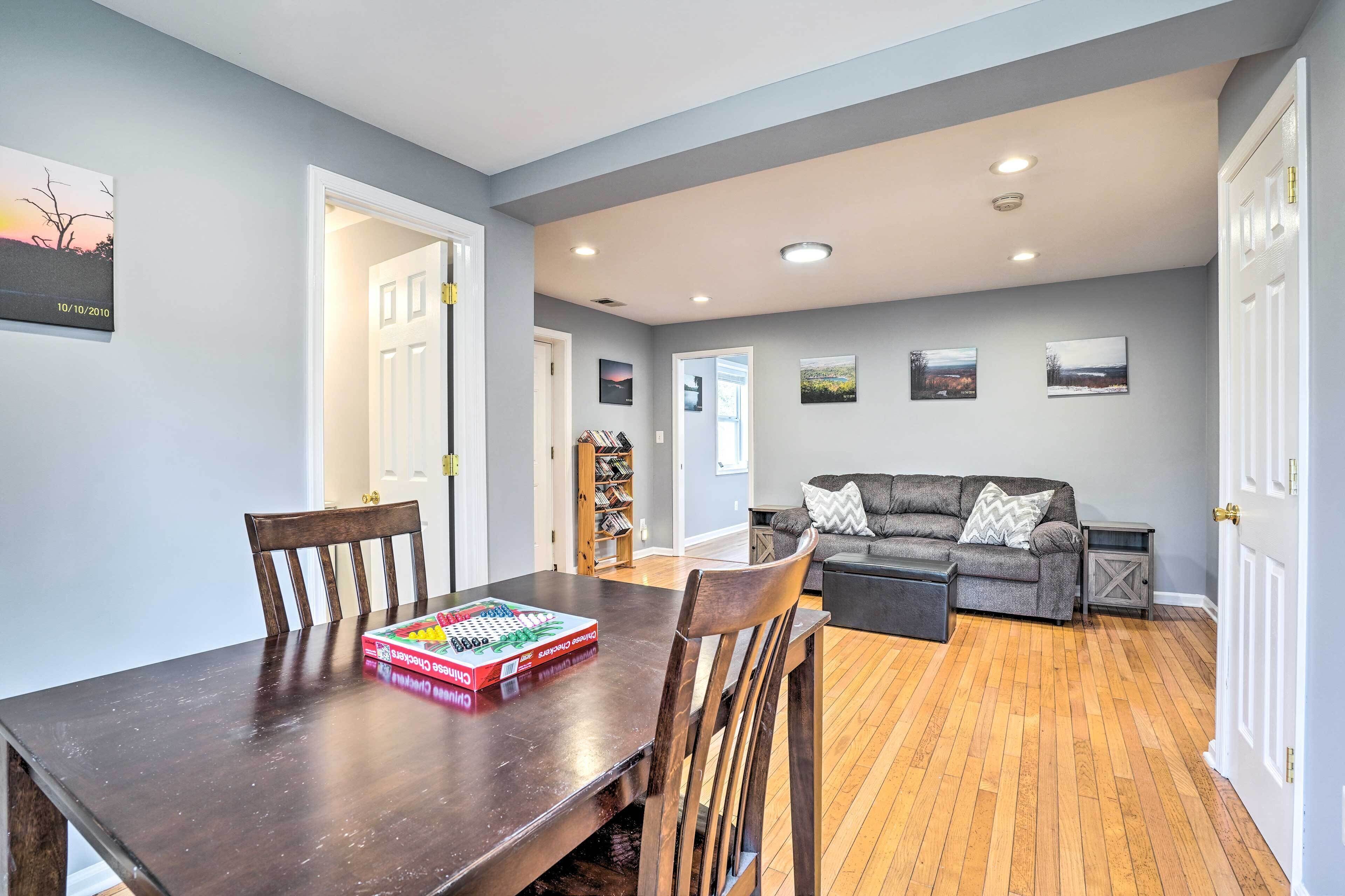 A dining area with a wooden table and chairs, a board game, and a bookshelf in the background.
