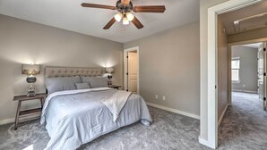 A bedroom with a bed, nightstands, a ceiling fan, and a door leading to another room. - Charming Springdale Townhome ~ 5 Mi to Dtwn! (Springdale)