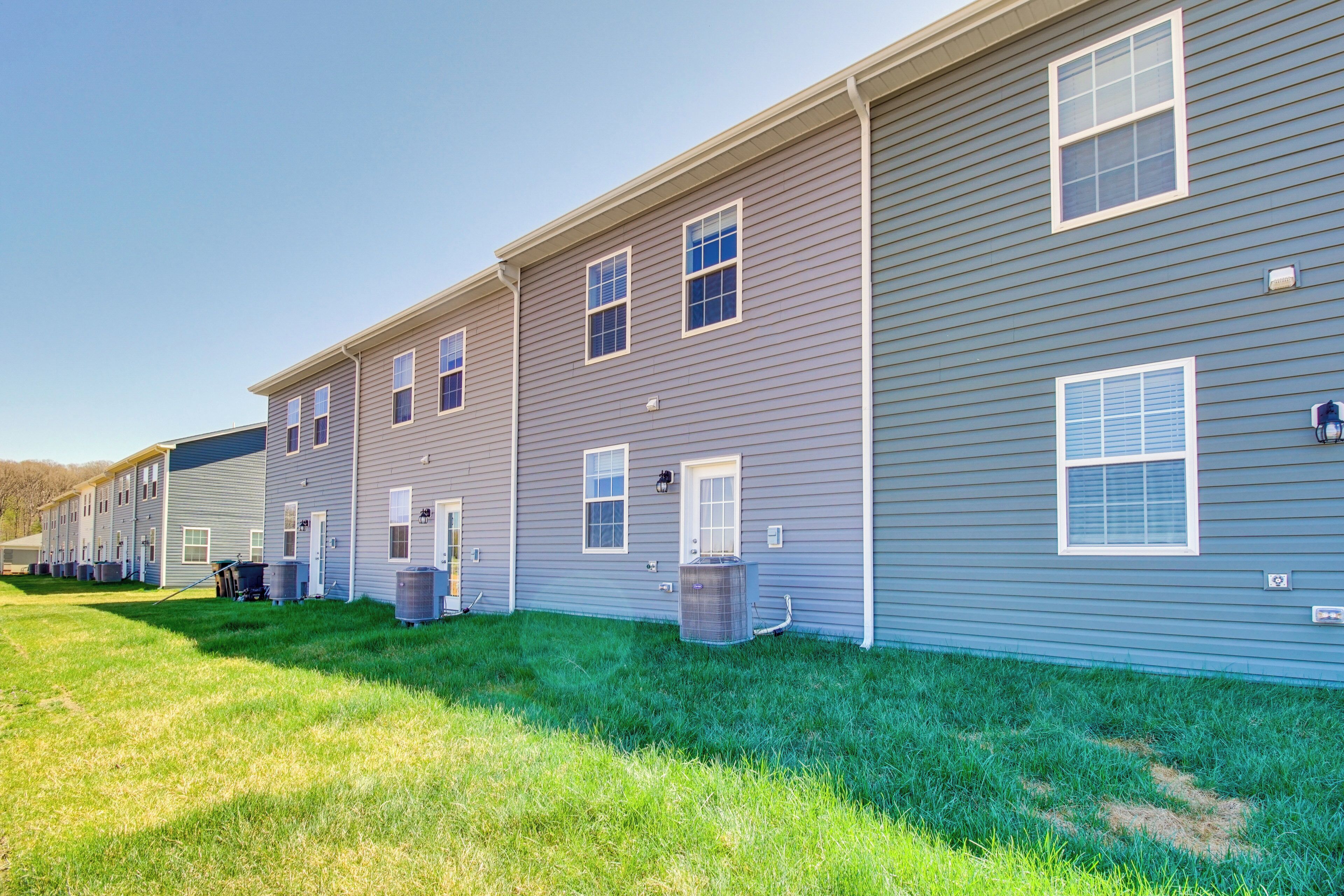 A row of two-story townhouses with a grassy front yard and a clear sky.