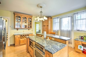 Una cocina con armarios de madera, encimeras de granito, horno empotrado y refrigerador.