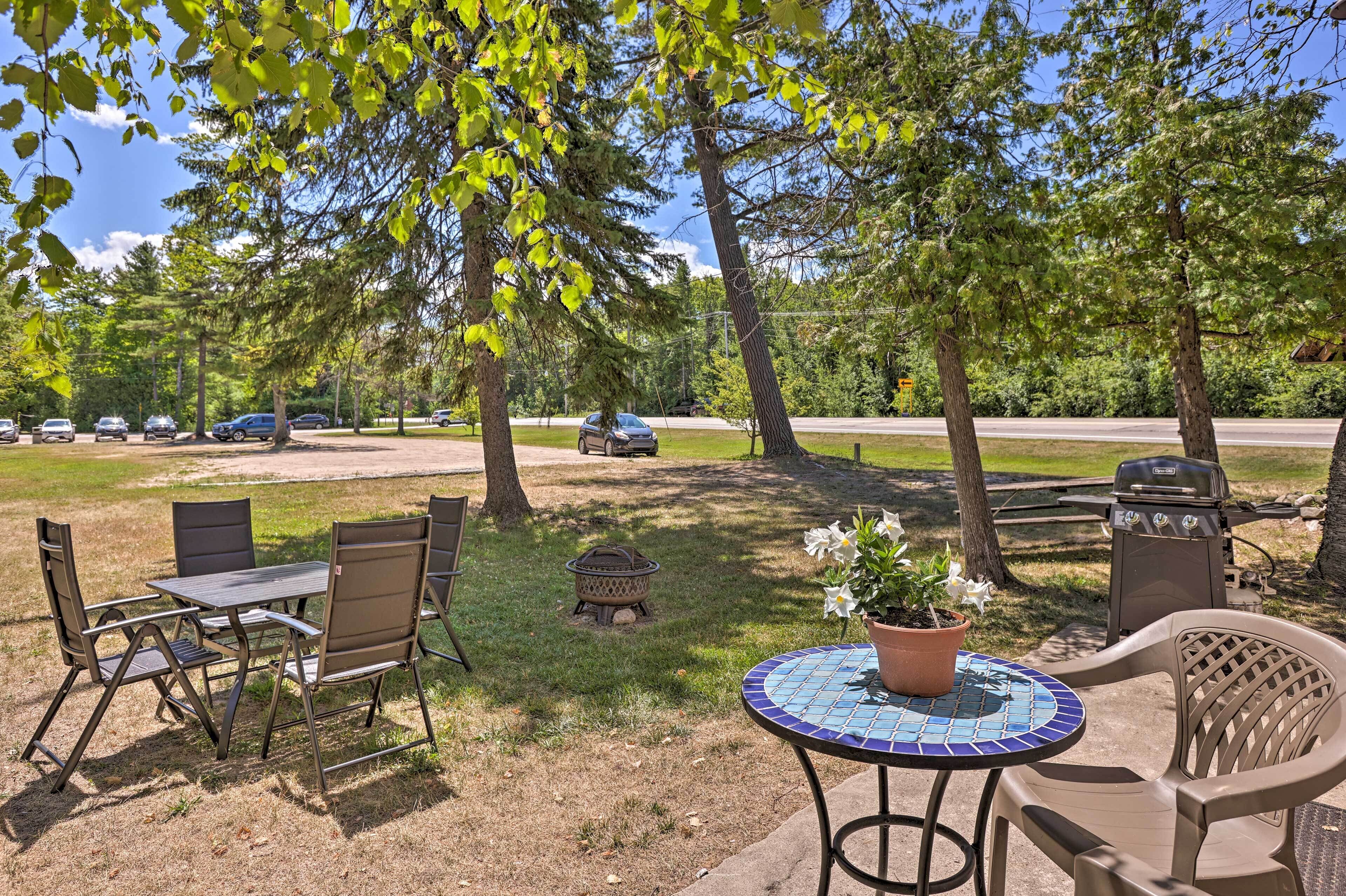 Une terrasse extérieure avec une table et des chaises, un barbecue et un foyer.