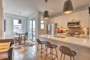 A modern kitchen with a central island, stainless steel appliances, and bar stools.