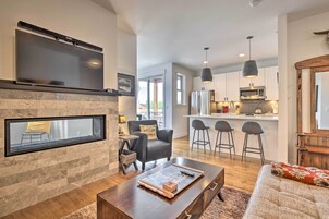 A modern living room with a fireplace, a flat-screen TV mounted above it, and a cozy seating area with a sofa and a coffee table.