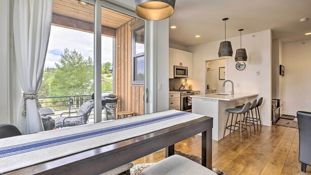 A modern kitchen with a central island, bar stools, and pendant lighting. - Grand Lake Condo w/ Balcony & Mountain Views (Grand Lake)