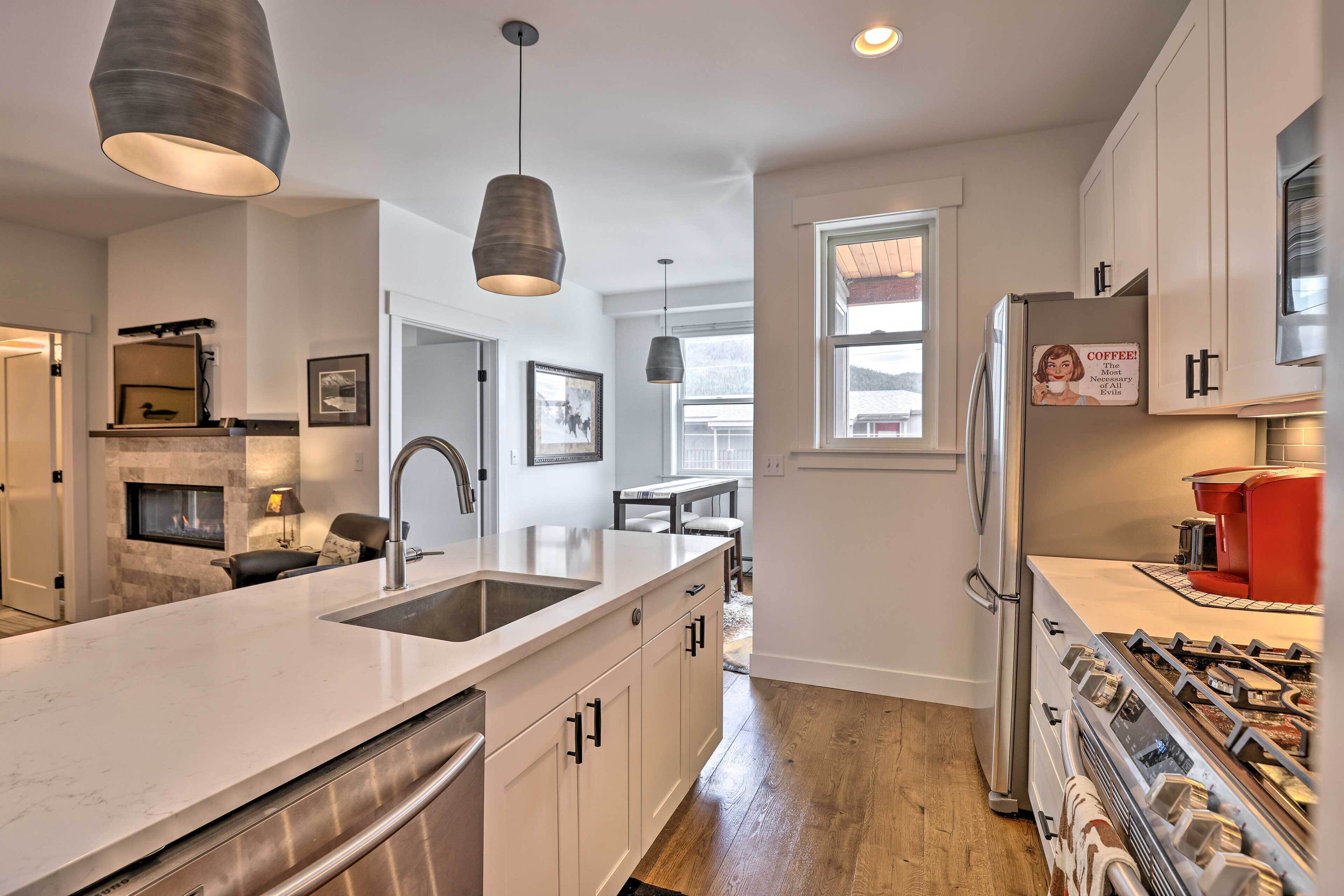 A modern kitchen with a central island, stainless steel appliances, and pendant lighting.