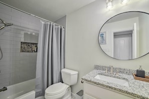 A bathroom with a shower, toilet, sink, and a mirror.