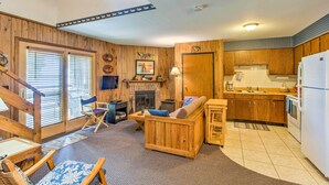 A cozy living room with a fireplace, wooden furniture, and a kitchen area with wooden cabinets and a refrigerator. - Clearwater Lake Getaway w/ Shared Pool & Boat Dock (Annandale)