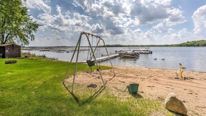 A lakeside view with a swing set, dock, and grassy area. - Clearwater Lake Getaway w/ Shared Pool & Boat Dock (Annandale)