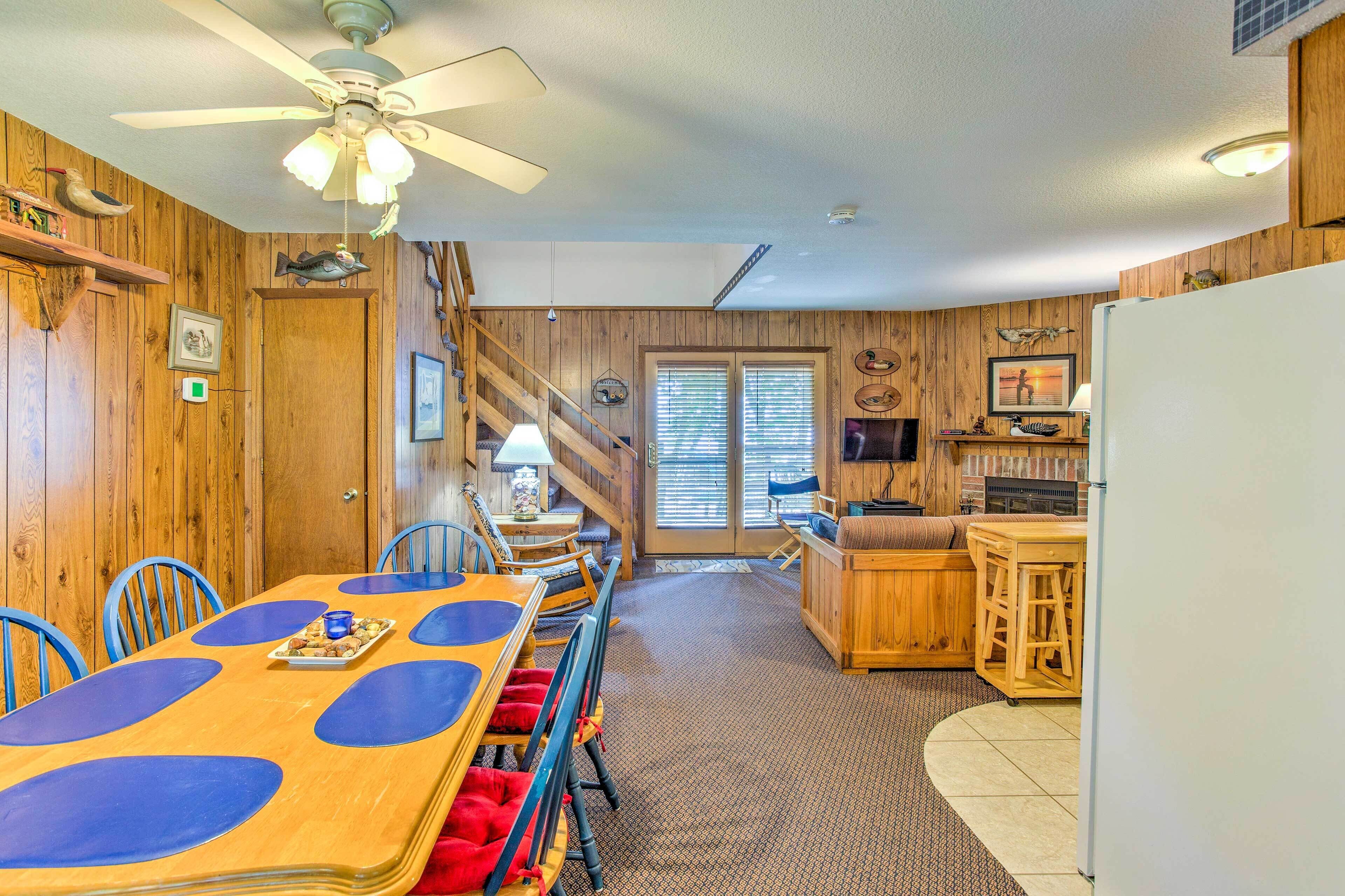 Un intérieur en bois comprenant une table à manger, des chaises, un coin cuisine et un ventilateur de plafond.