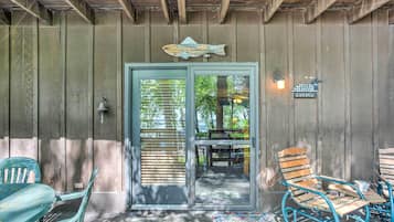 A covered porch with wooden walls, a fish-shaped decoration, and a welcome sign.