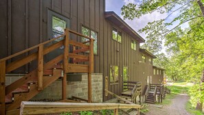 A wooden cabin with a wooden staircase leading to a deck, surrounded by trees and a gravel path. - Clearwater Lake Getaway w/ Shared Pool & Boat Dock (Annandale)