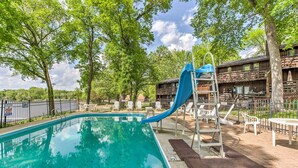 A swimming pool with a blue slide, surrounded by trees and outdoor seating. - Clearwater Lake Getaway w/ Shared Pool & Boat Dock (Annandale)
