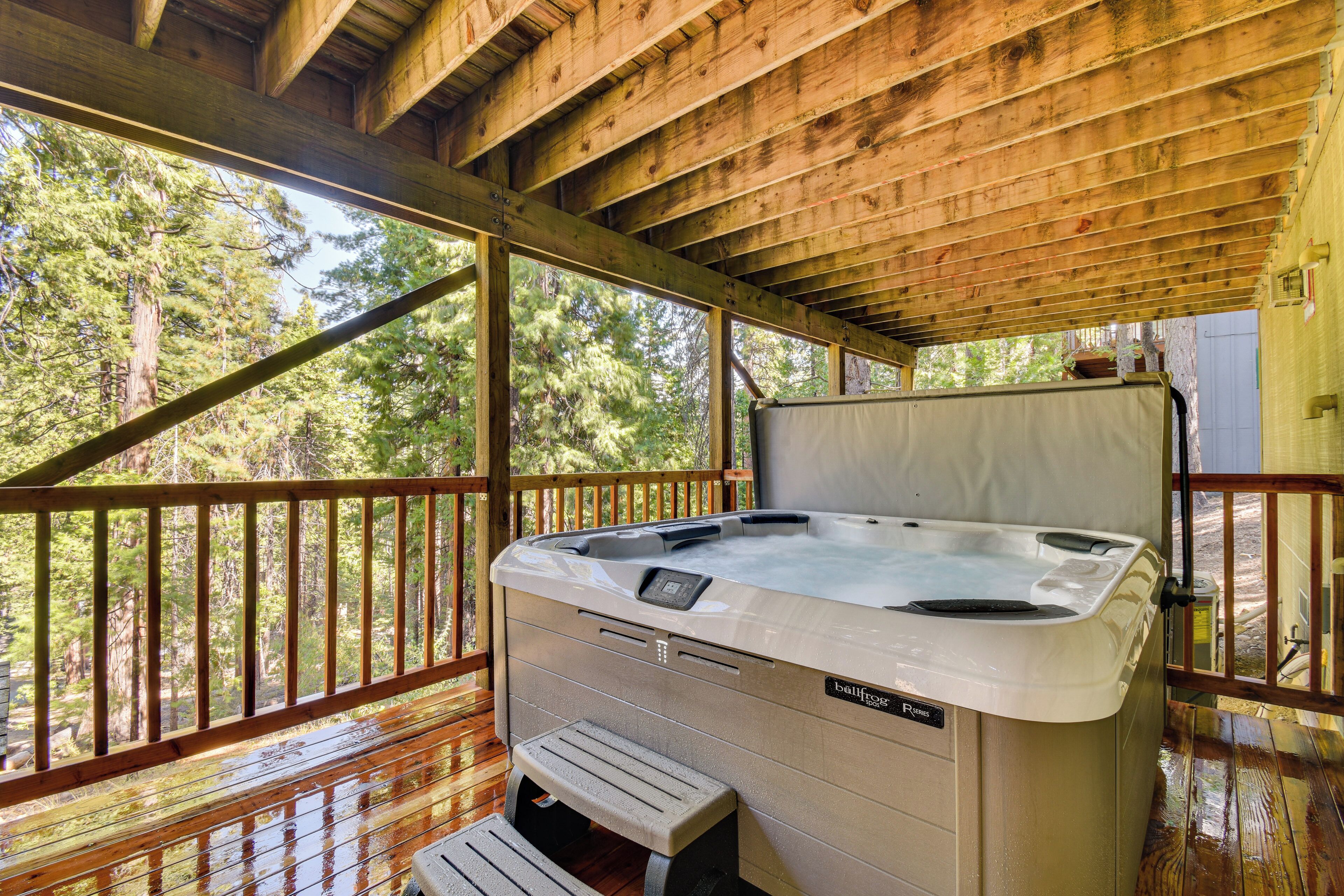 Un jacuzzi en una terraza de madera con vista a un bosque.
