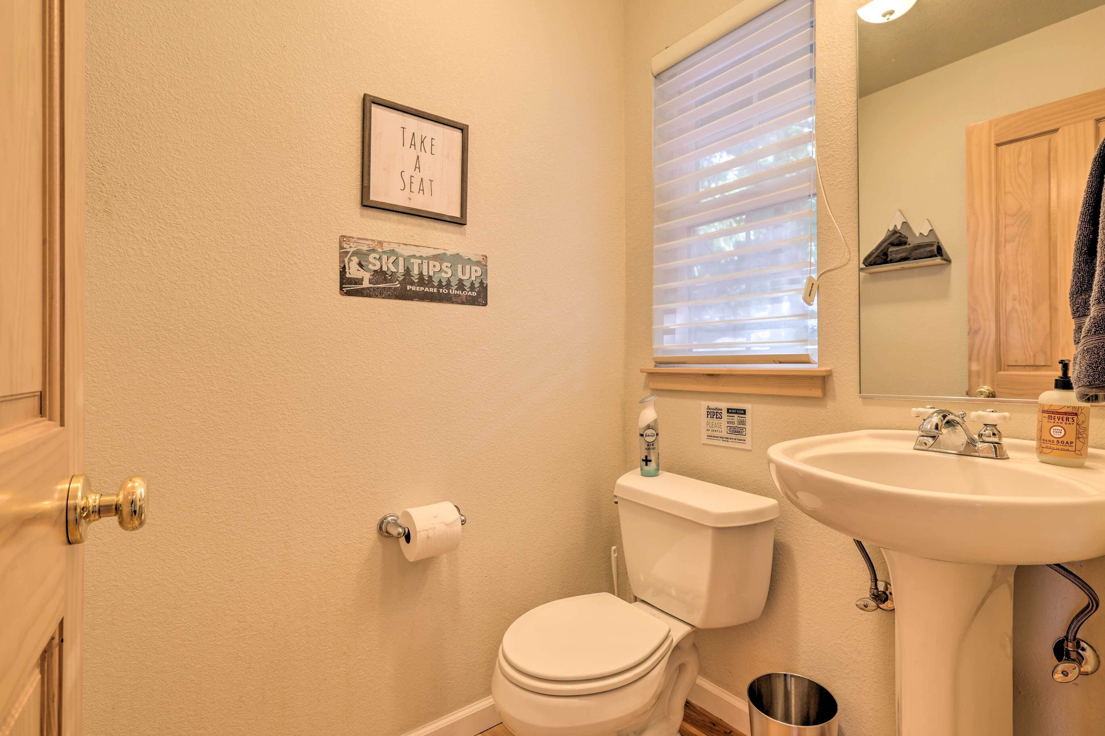 Une salle de bain avec des toilettes, un lavabo et une fenêtre avec des stores.