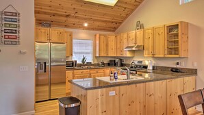 A modern kitchen with wooden cabinets, stainless steel appliances, and a granite countertop. - Cold Springs Mountain Cabin: Hot Tub & Generator (Long Barn)