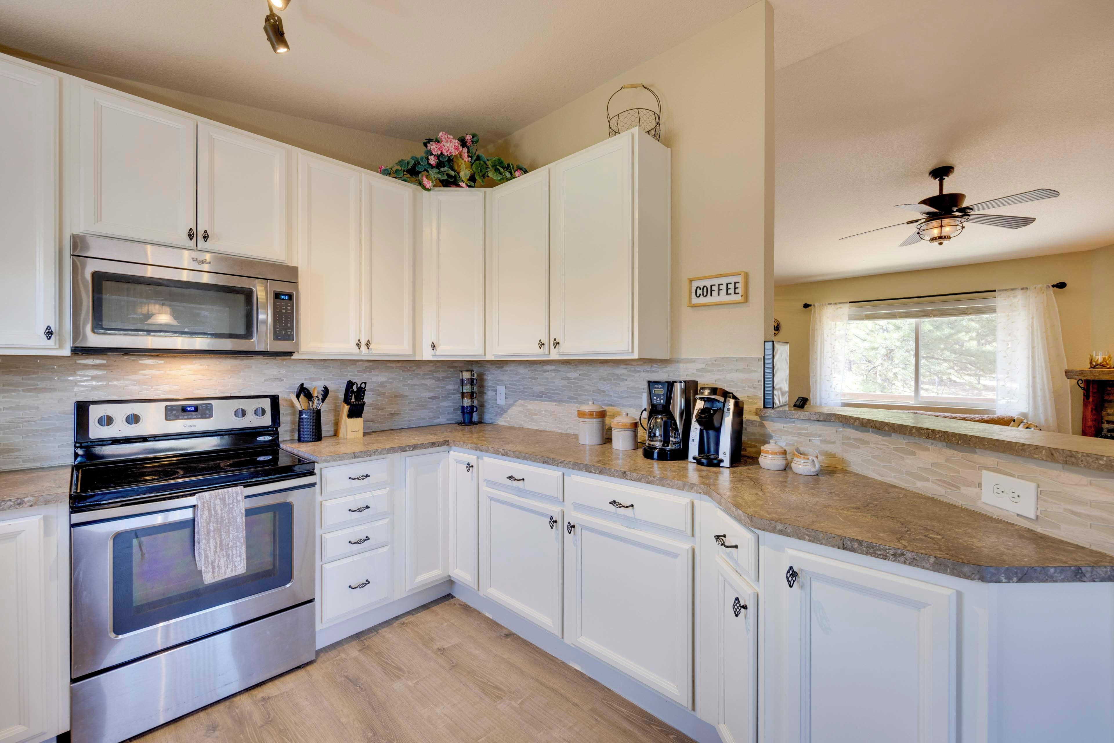 A kitchen with white cabinets, a stainless steel oven, a microwave, and a coffee maker.