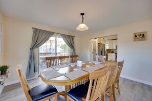 Un coin repas avec une table ronde en bois, six chaises et un luminaire suspendu.