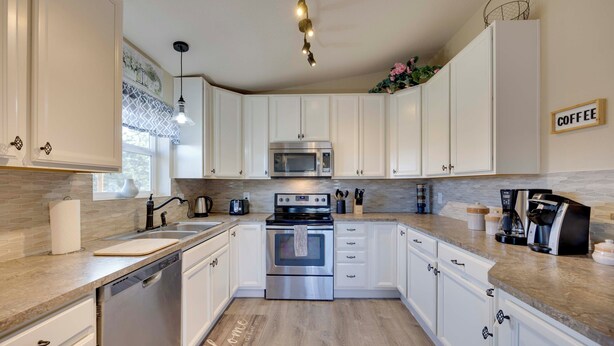Una cocina moderna con armarios blancos, electrodomésticos de acero inoxidable y encimera de madera.