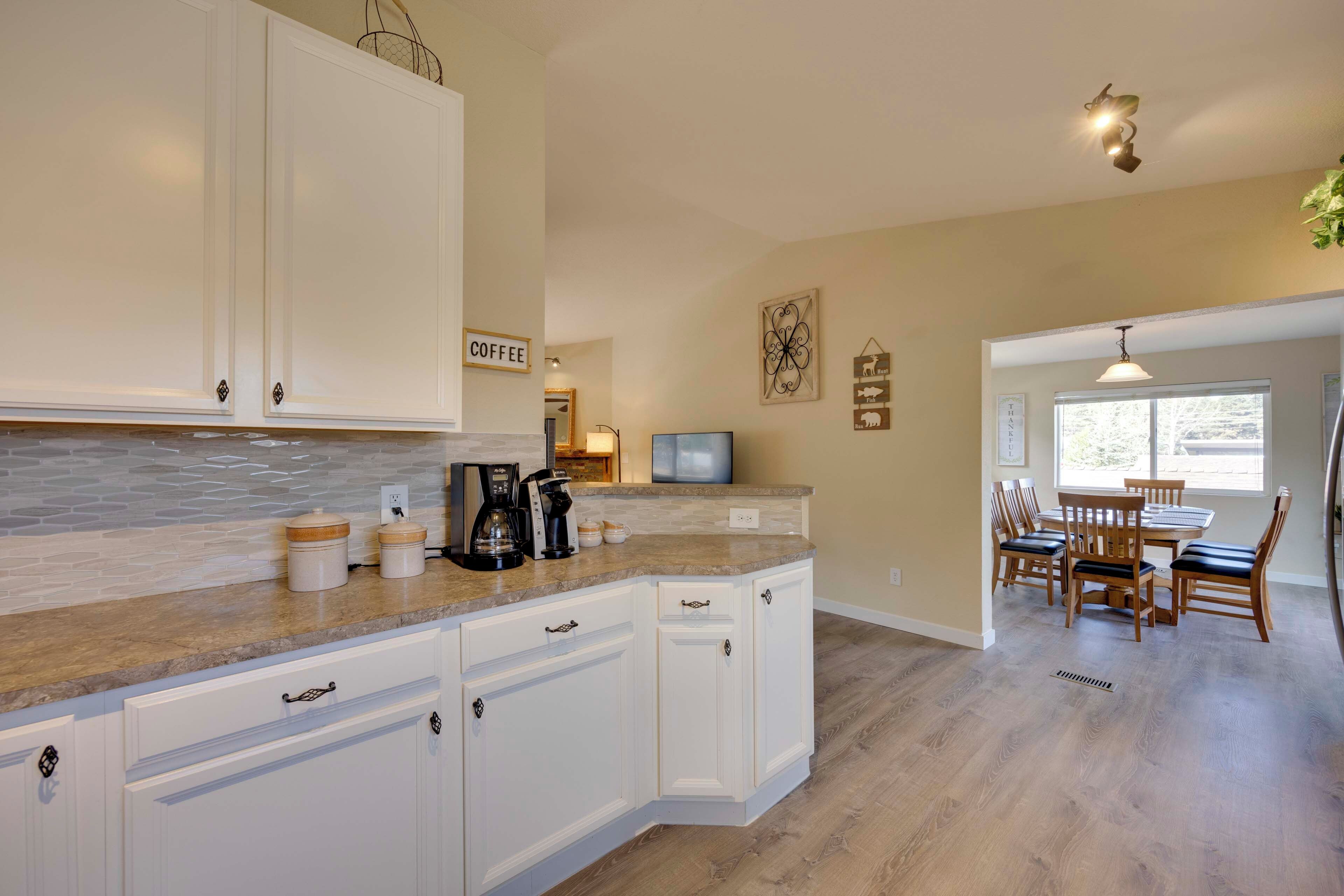 A kitchen with white cabinets, a marble countertop, and a coffee station.