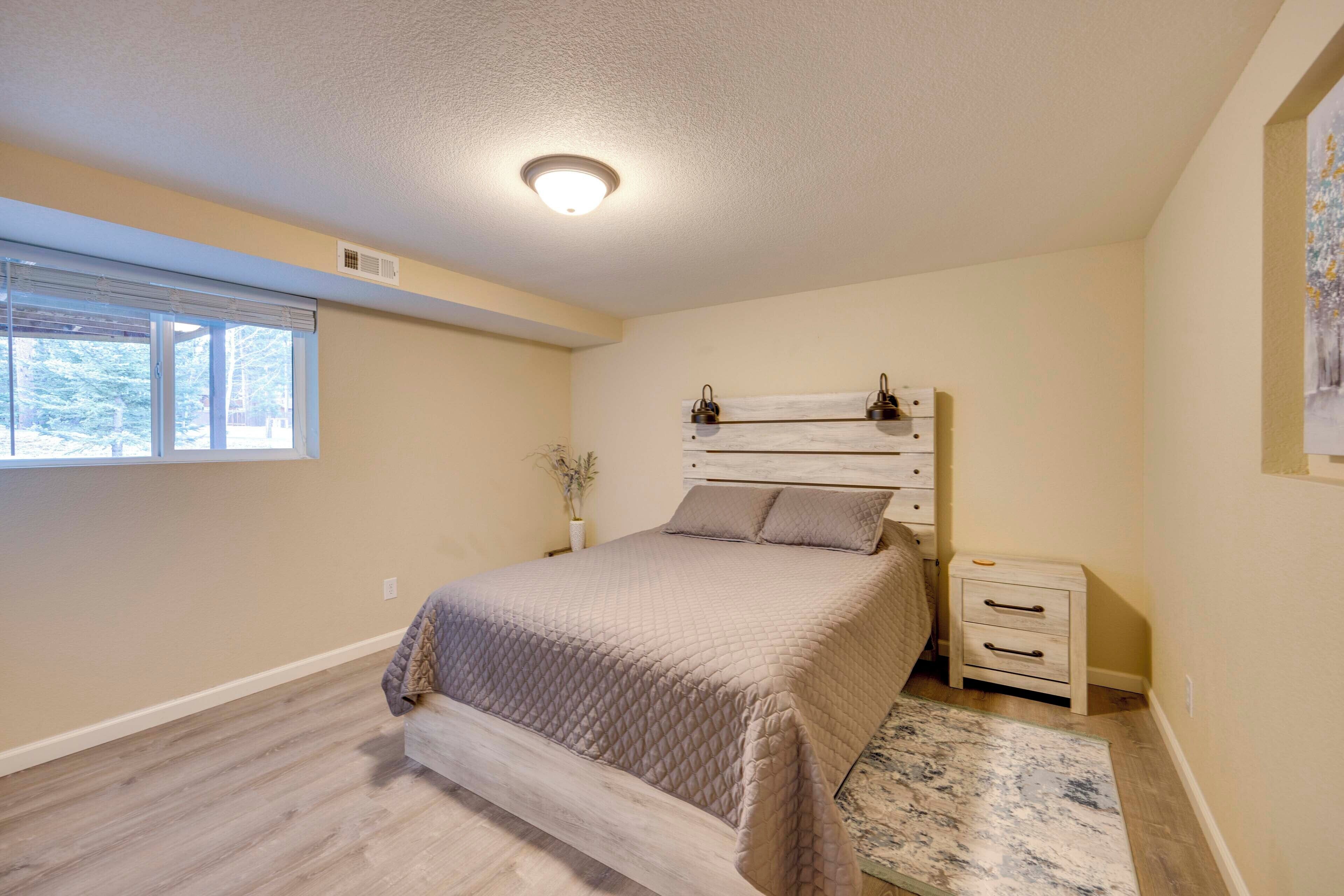 A bedroom with a bed, a nightstand, a window, and a ceiling light.