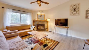 Una sala de estar con sofá, mesa de centro, chimenea, televisor y ventilador de techo.