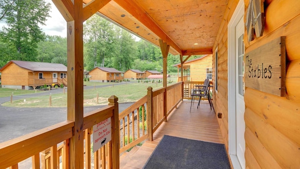 A wooden cabin with a porch, a sign reading "The Stables", and a warning sign about dogs. - Fire Pit: Cozy Bryson City Cabin on Tuck River (Bryson City)