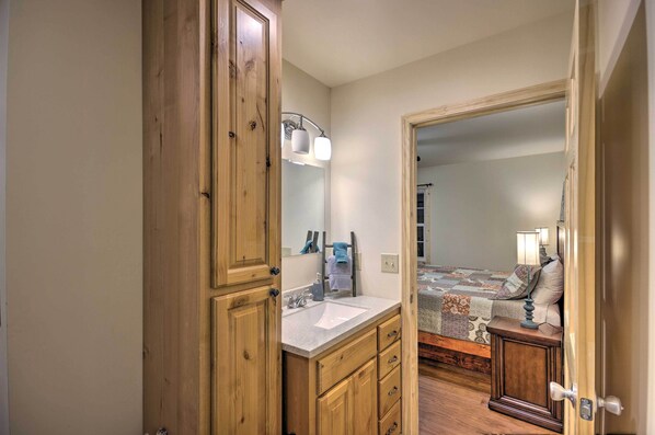Un dormitorio con un armario de madera, una mesita de noche con lámpara y una cama con manta estampada.