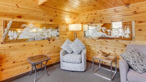 L’intérieur d’un chalet en bois chaleureux et accueillant, avec un fauteuil rembourré, une petite table et un canapé.