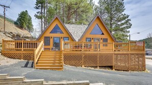 Une cabane dotée d’une terrasse en bois et d’un escalier menant à une porte.