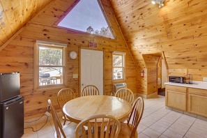A cozy wooden cabin with a dining area, kitchen, and an exit sign. - Cozy Keystone Cabin: Hot Tub, 3 Mi to Mt Rushmore! (Keystone)