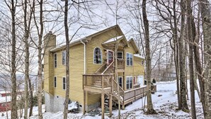 Une maison à deux étages avec une terrasse en bois et un escalier menant à un balcon.