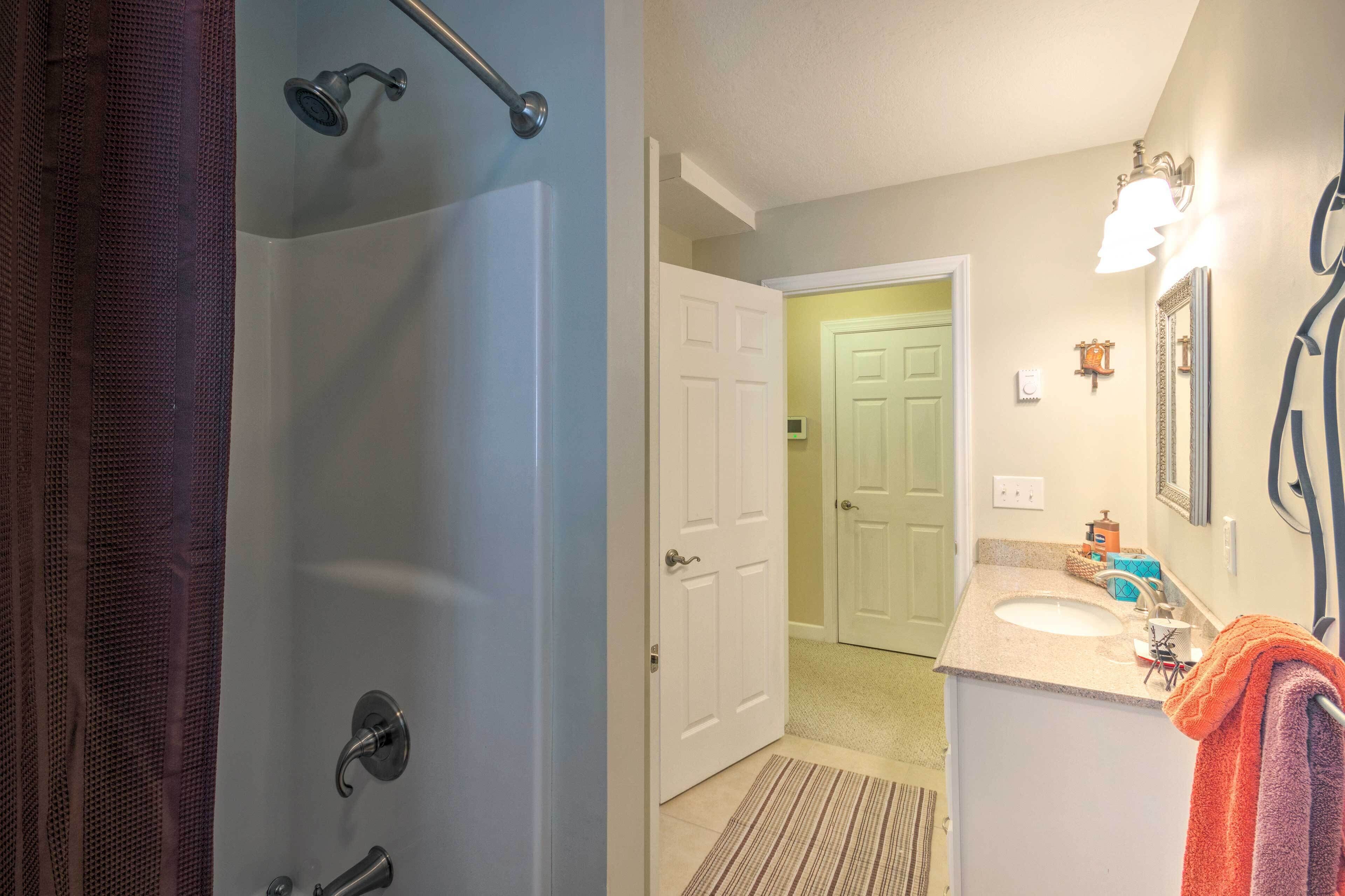 A bathroom with a shower, a sink, and a mirror.