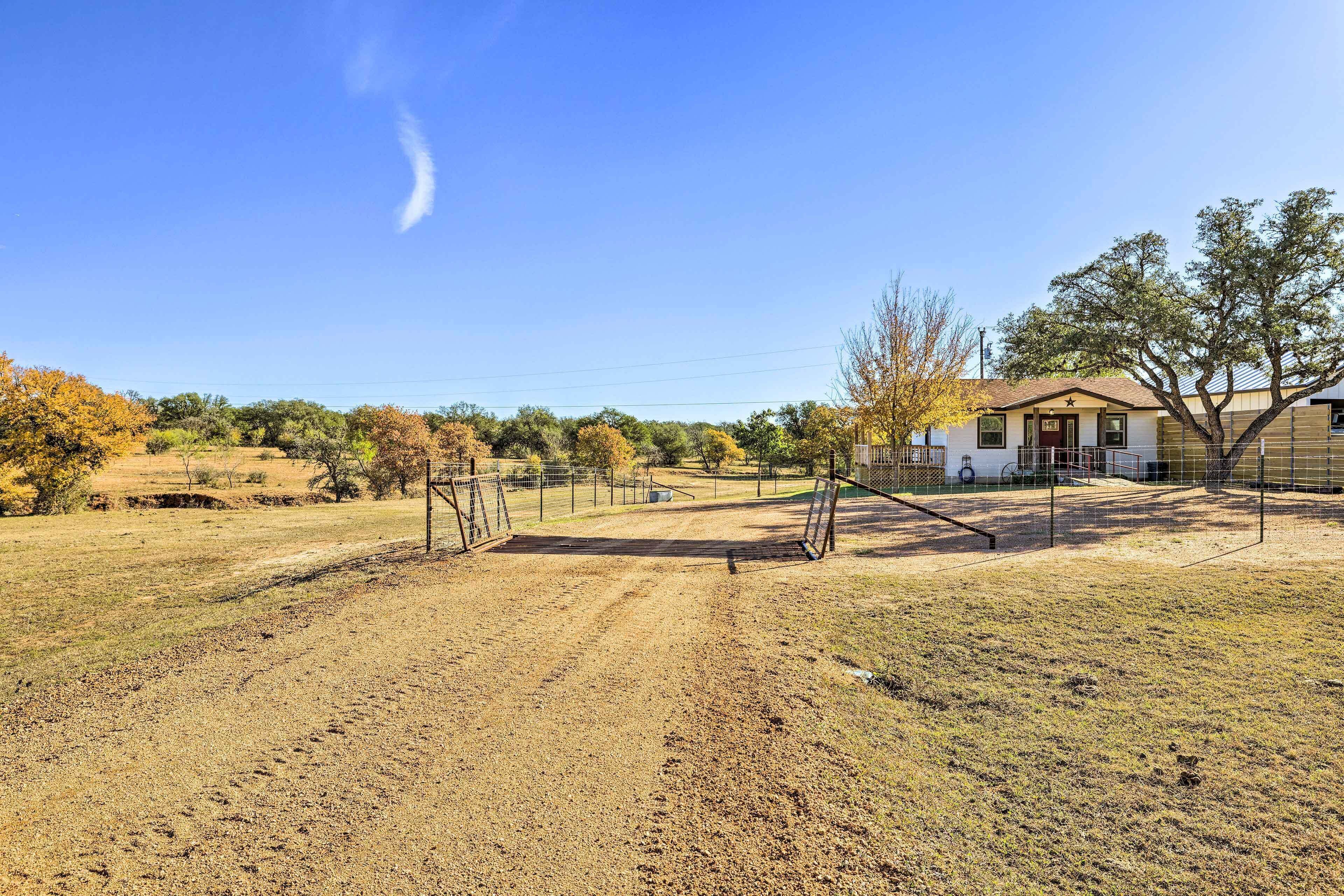 A fenced outdoor area with a dirt path leading to a house.