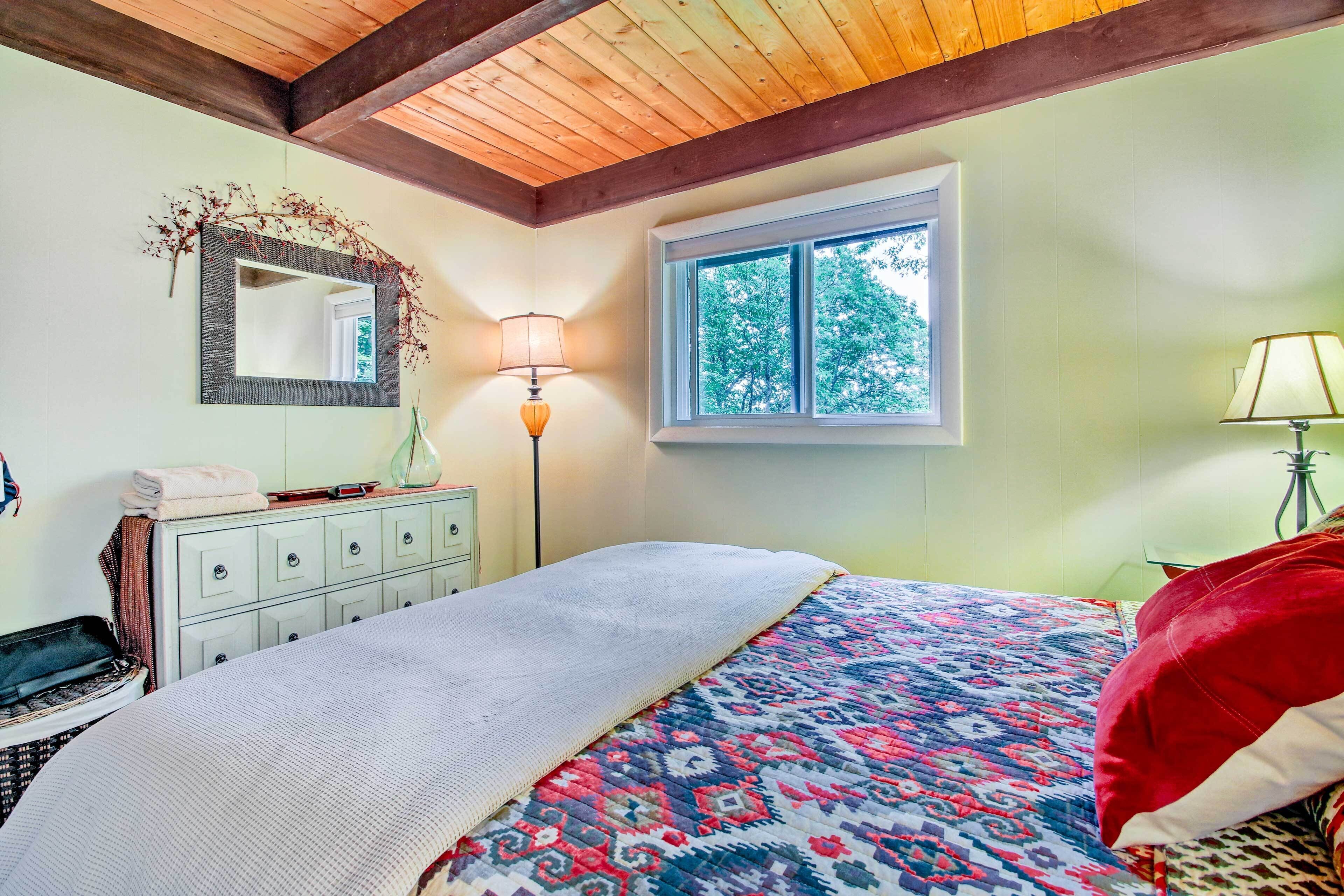 Une chambre à coucher comprenant un lit, une commode, un miroir et deux lampes.